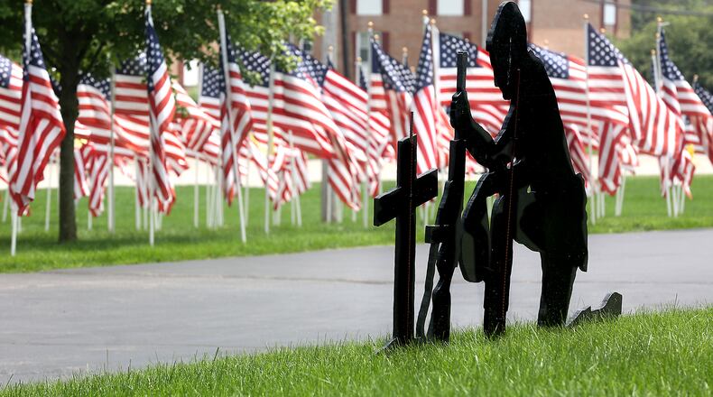 A wooden cutout of a soldier kneeling at a comrade's grave stands out against the American flags in the Honor Field memorial display at Jackson Lytle & Lewis Life Celebration Center in Springfield in this file photo. BILL LACKEY/STAFF