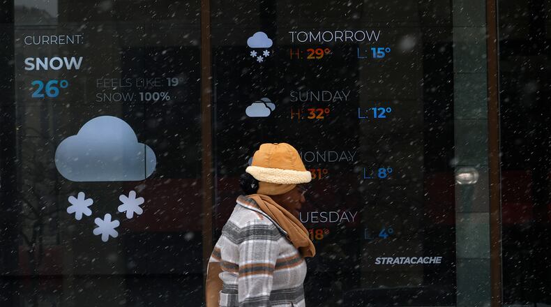 A lady walks by the Stratacache building weather board on Main Street, Friday, Jan. 10, 2025. MARSHALL GORBY\STAFF