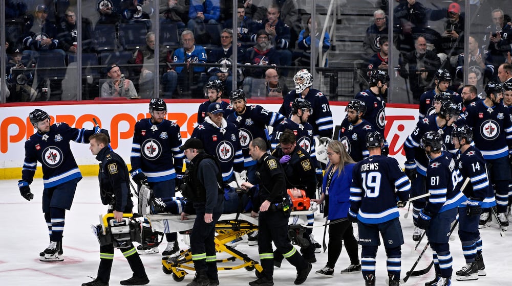 Winnipeg Jets' Haydn Fleury is helped off the ice after being injured against the Vegas Golden Knights during the first period of their NHL hockey game in Winnipeg, Tuesday Jan. 6, 2026. (Fred Greenslade/The Canadian Press via AP)