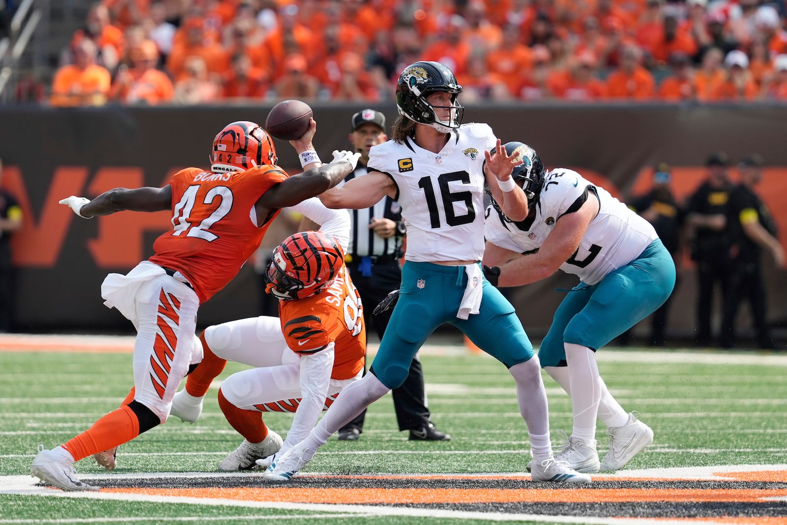 Jacksonville Jaguars quarterback Trevor Lawrence (16) throws under pressure from Cincinnati Bengals linebacker Oren Burks (42) during the second half of an NFL football game, Sunday, Sept. 14, 2025, in Cincinnati. (AP Photo/Carolyn Kaster)