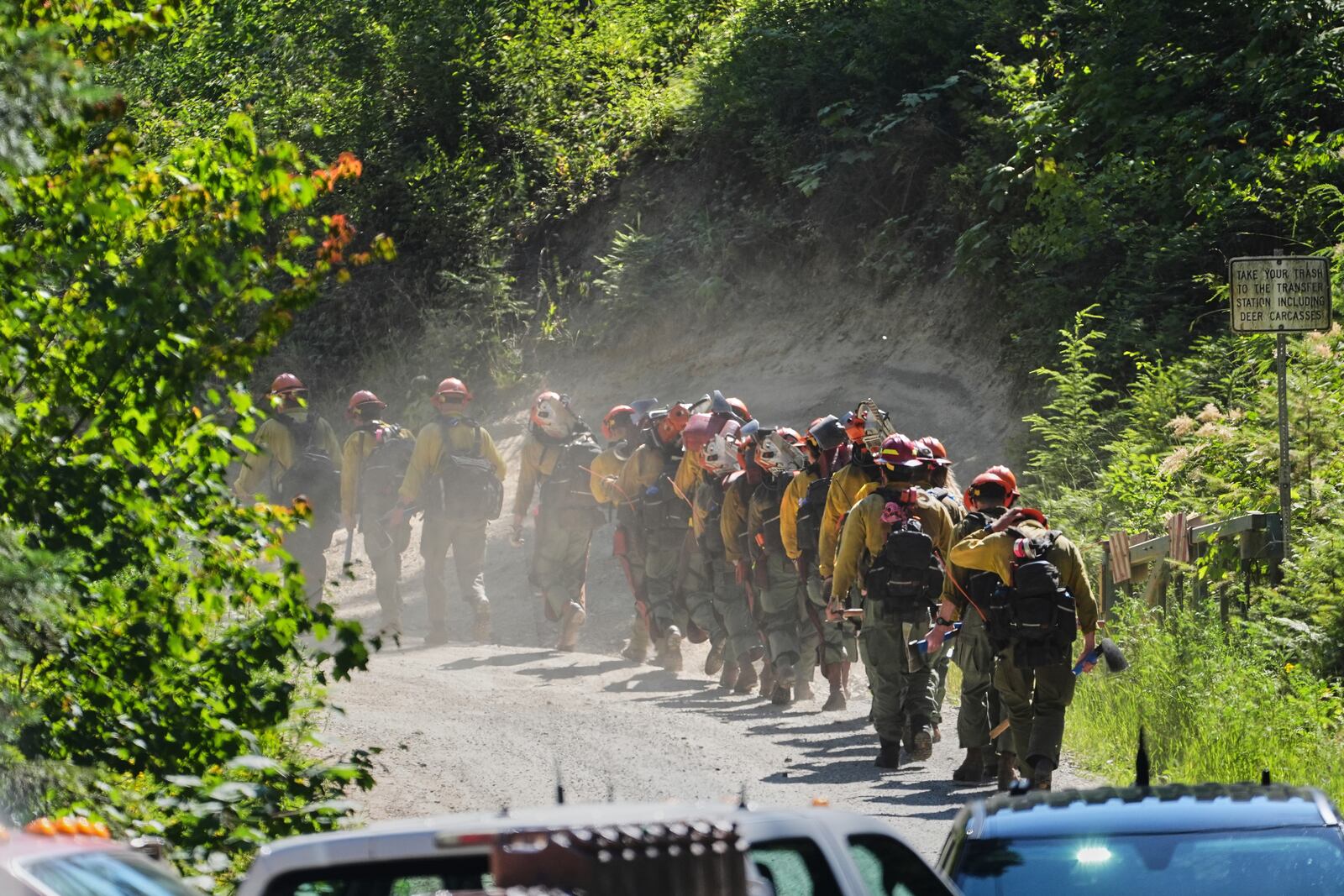 A line of wildland firefighters arrive at the scene the day after a shooter ambushed and killed multiple firefighters responding to a wildfire at Canfield Mountain Monday, June 30, 2025, in Coeur D'Alene, Idaho. (AP Photo/Lindsey Wasson)