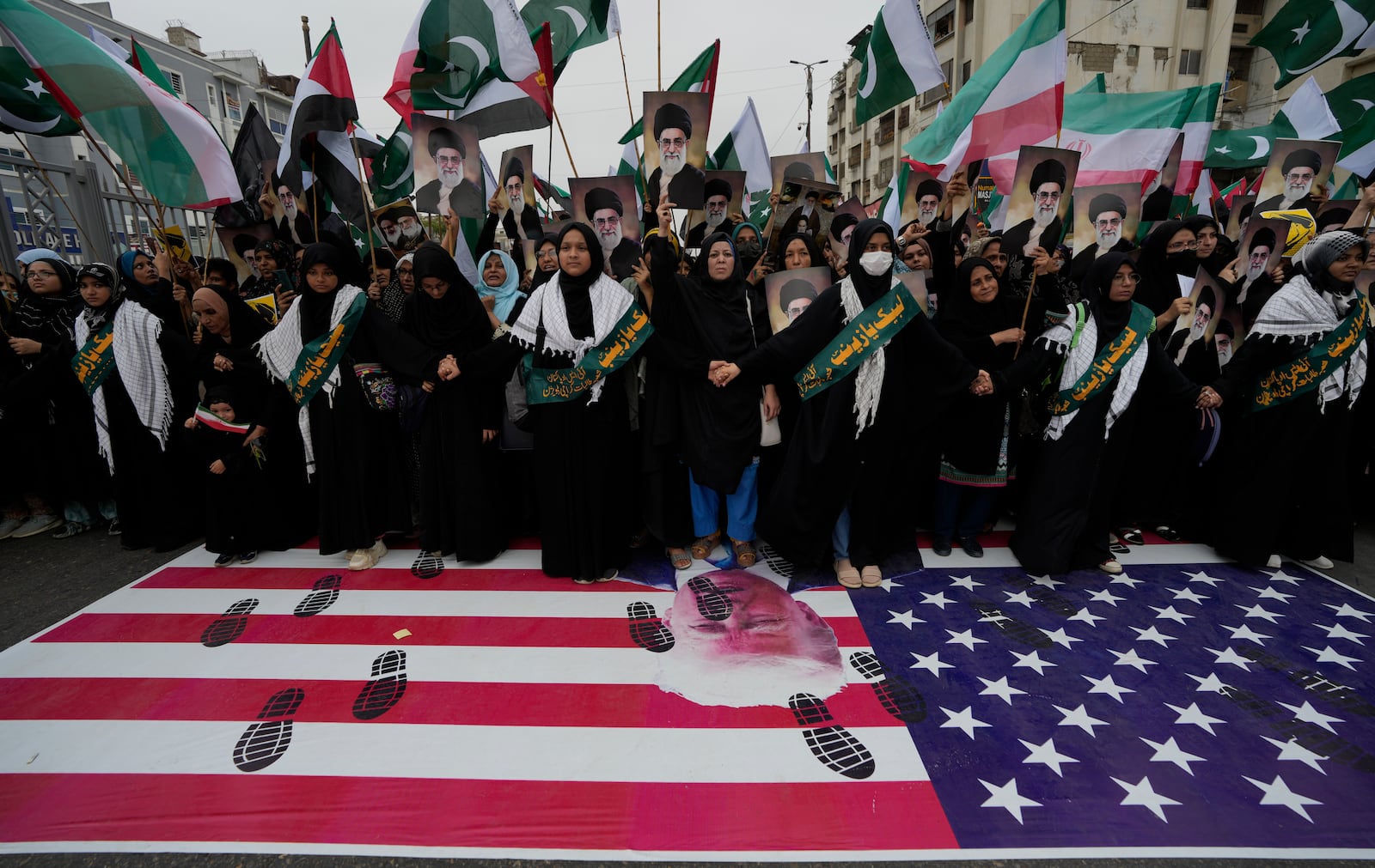 Shiite Muslims stand over a representation of U.S flag during a rally to condemn Israeli strikes on Iran, in Karachi, Pakistan, Sunday, June 22, 2025. (AP Photo/Fareed Khan)