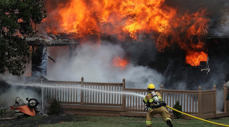 A Moorefield Township firefighter rushes into position to attack a fully engulfed house fire soon after arriving on the scene on Thomaston Trail Thursday. The homeowners were not home at the time of the blaze.
