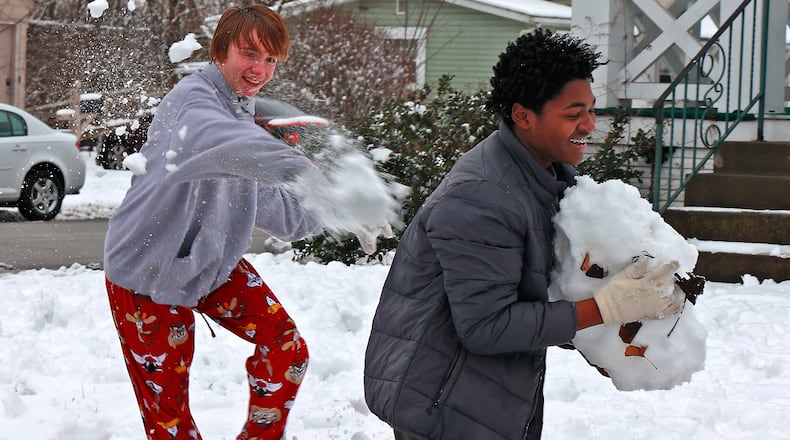 Hayden Frederick hits Antonio Crowe in the back with a snowball as Antonio packs together a giant snowball of his own Monday, Jan. 23, 2023 while the two friends have a snowball fight along East Cecil Avenue in Springfield. The duo were enjoying their day off school due to the weather. BILL LACKEY/STAFF