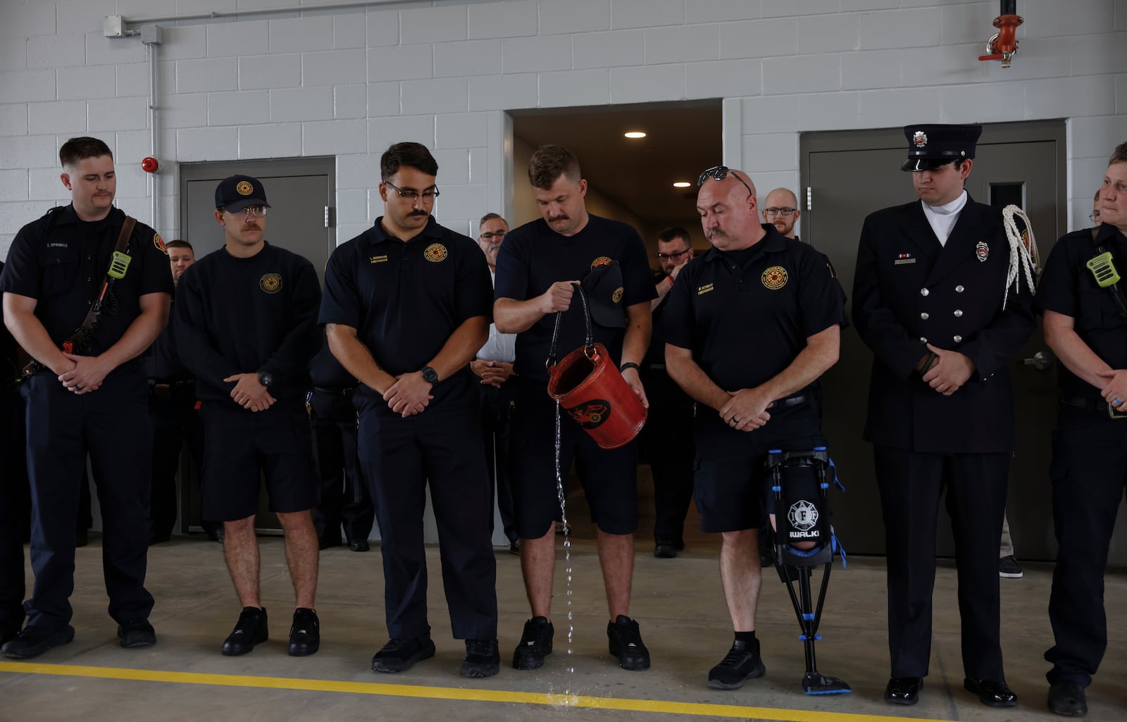 Springfield firefighter Blake Lockwood, center, pours water to the ground as a way to "pass the torch" during a ceremony to celebrate the opening of Springfield Fire Station 6 on Tuesday, June 17, 2025, on South Charleston Pike. JOSEPH COOKE/STAFF