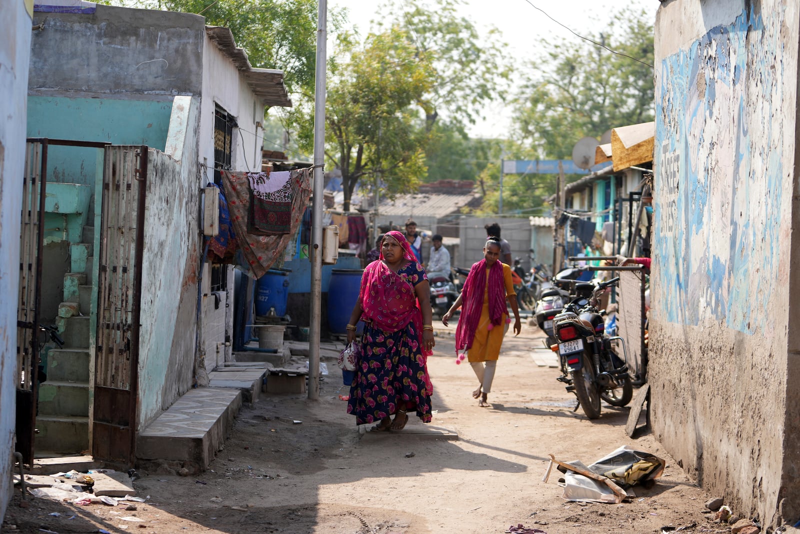 People walk through buildings in Vanzara Vas, a low-income neighborhood, in Ahmedabad, India, Wednesday, April 2, 2025. (AP Photo/Ajit Solanki)