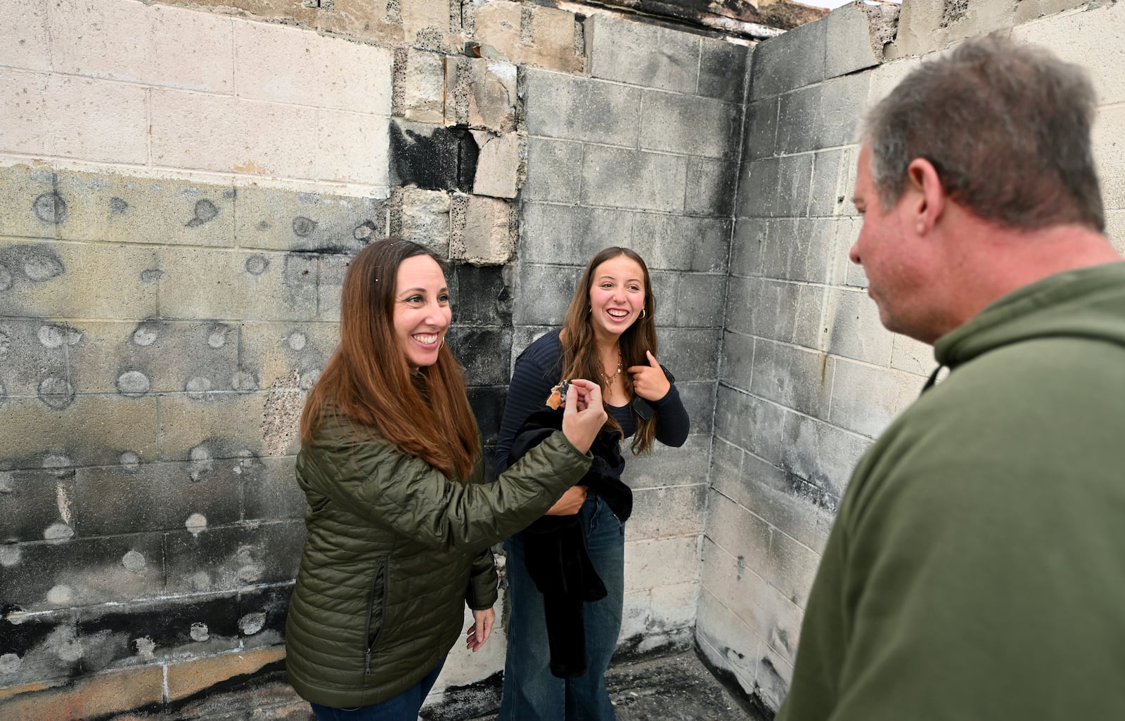 Rachel McNett, left, finds a piece of her old passport as daughter Teagan and husband Keith look on as they visit there house that burned in the Mountain Fire Wednesday, April 16, 2025, in Camarillo, Calif. (AP Photo/Wally Skalij)