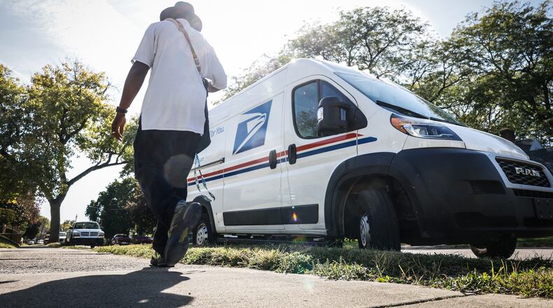 A mail carrier walks back to his truck after picking up and delivering mail on the eastside of Dayton. JIM NOELKER/STAFF