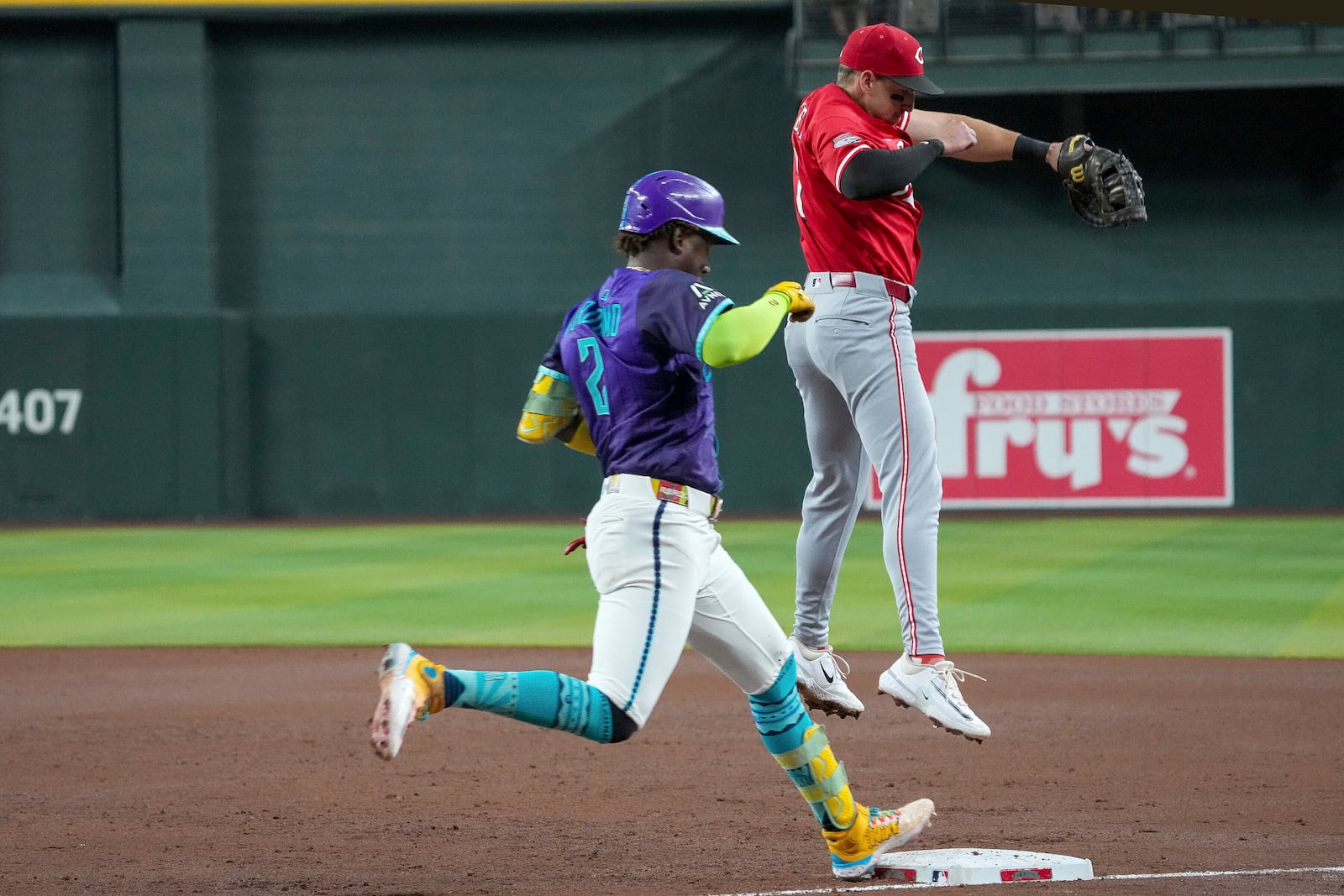 Arizona Diamondbacks' Geraldo Perdomo, left, beats the throw to first base after Cincinnati Reds first base Spencer Steer had to jump for the throw during the third inning of a baseball game Saturday, Aug. 23, 2025, in Phoenix. (AP Photo/Darryl Webb)