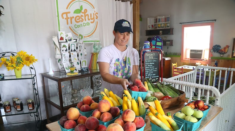 Elizabeth Thompson sets out fresh produce in Freshy's Corn Crib Friday, July 29, 2022. BILL LACKEY/STAFF