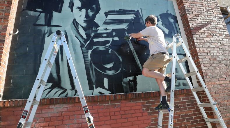 W.E. Arnold, along with Pete Hrinko and Shem Schutte, works on a mural of famous Springfield photographer Berenice Abbott on the exterior wall of Mother Stewart’s Brewery Sunday. BILL LACKEY/STAFF