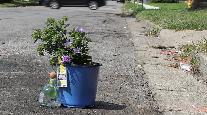 Flowers and a makeshift memorial sit along Euclid Avenue where a man was shot and killed in a car parked in the spot in 2020. BILL LACKEY/STAFF
