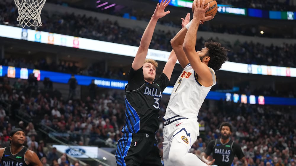 Denver Nuggets guard Jamal Murray, right, goes up for a basket against Dallas Mavericks forward Cooper Flagg during the first half of an NBA basketball game Wednesday, Jan. 14, 2026, in Dallas. (AP Photo/Julio Cortez)