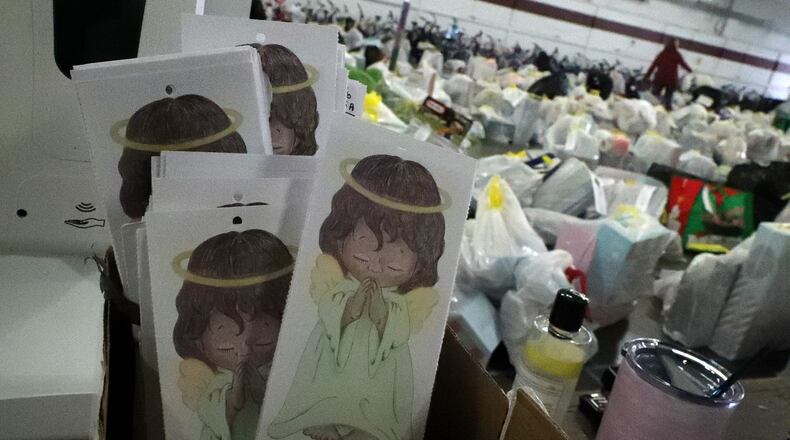 Angel Tags with needy children's names on then sit in a box as a volunteer sorts through donated toys in the background. BILL LACKEY/STAFF