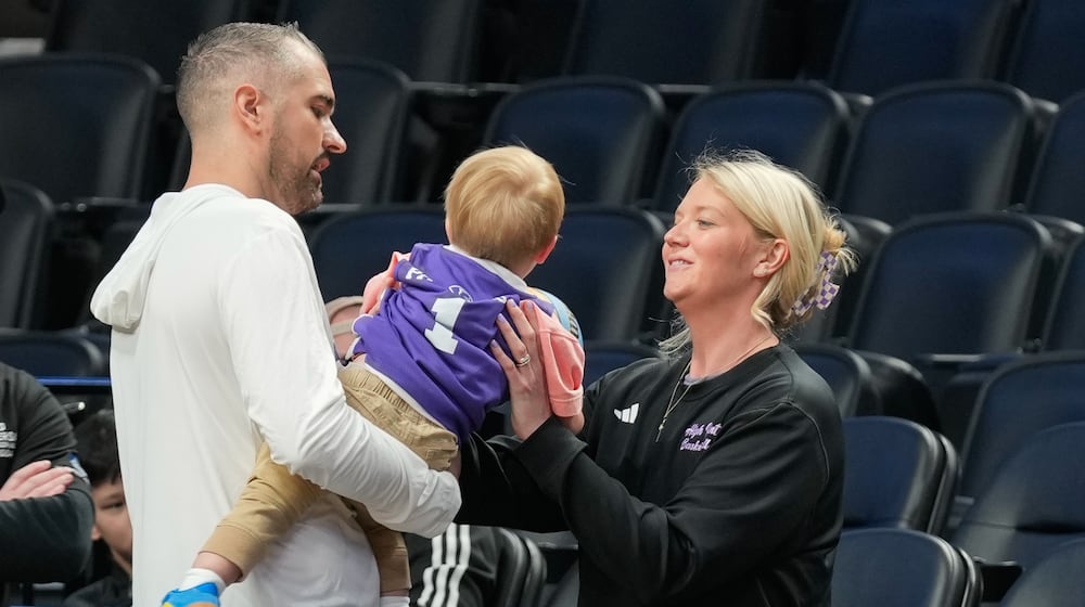 High Point head coach Flynn Clayman, left, hands his son, Quinn, to his wife Katie Clayman, assistant coach for the High Point women's basketball team, right, during practice prior to the first round of the NCAA college basketball tournament on Wednesday, March 18, 2026, in Portland, Ore. (AP Photo/Jenny Kane)