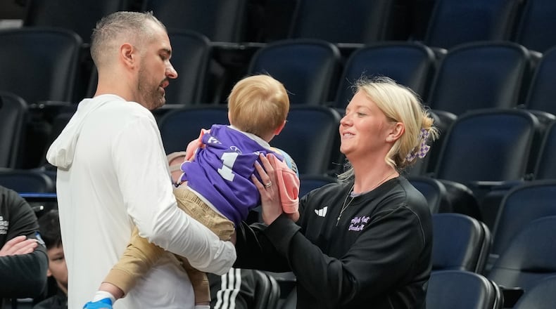 High Point head coach Flynn Clayman, left, hands his son, Quinn, to his wife Katie Clayman, assistant coach for the High Point women's basketball team, right, during practice prior to the first round of the NCAA college basketball tournament on Wednesday, March 18, 2026, in Portland, Ore. (AP Photo/Jenny Kane)