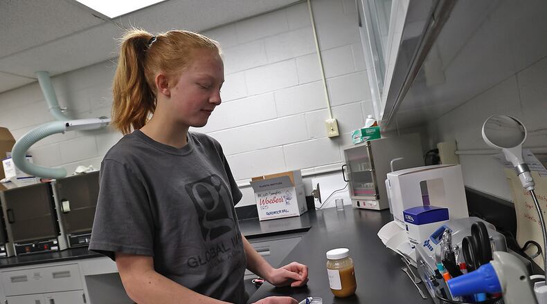 Tessa Holcomb, from the Global Impact STEM Academy, demonstrates the work she performed in the lab at Woeber's Mustard for her Capstone Internship. BILL LACKEY/STAFF