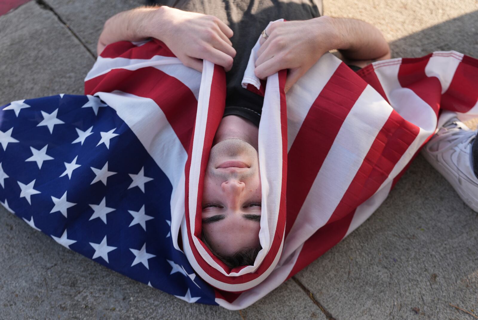FILE - A demonstrator wraps themselves with a U.S. flag during a protest outside Dodger Stadium, June 21, 2025, in Los Angeles. (AP Photo/Damian Dovarganes, file)