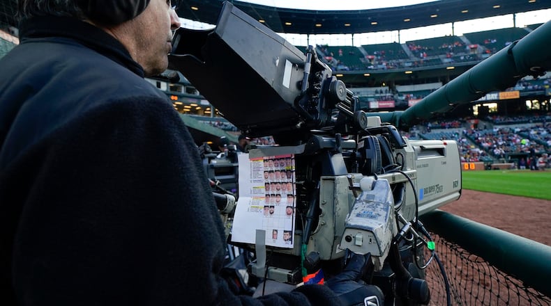 FILE - A sheet showing Boston Red Sox players photos hangs from a camera as a broadcast operator works during the first inning of a baseball game between the Baltimore Orioles and the Red Sox, Monday, April 24, 2023, in Baltimore, Md. (AP Photo/Julio Cortez, File)