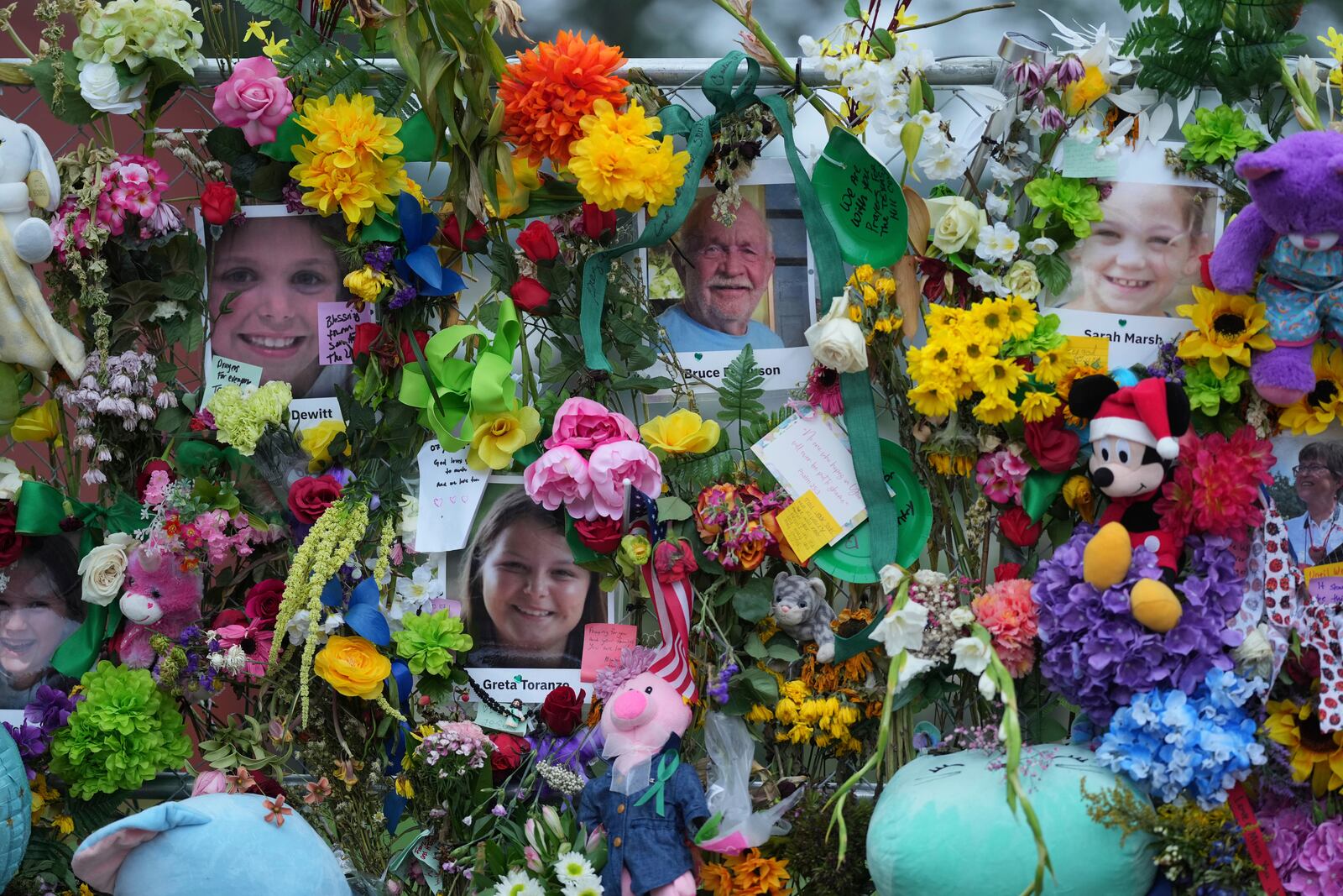 Photos of flood victims are posted with flowers, notes and other items on a memorial wall, Sunday, July 13, 2025, in Kerrville, Texas. (AP Photo/Eric Gay)