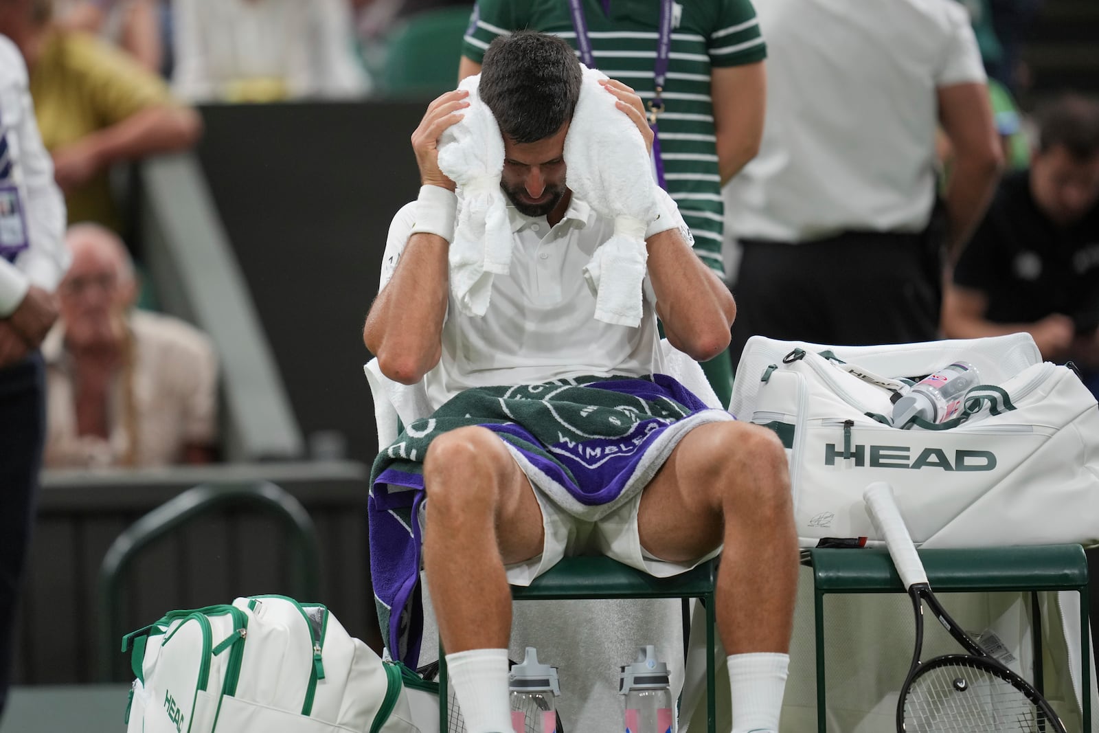 Novak Djokovic of Serbia places a cold towel around his head during a change of ends break against Alexandre Muller of France during their first round men's singles match at the Wimbledon Tennis Championships in London, Tuesday, July 1, 2025. (AP Photo/Kin Cheung)