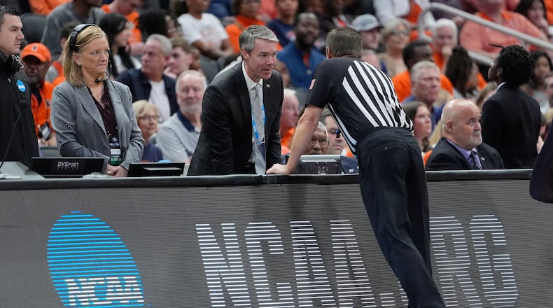 A referee talks with the scorer's table during an official's timeout due to a broken shot clock horn during the first half of an Elite Eight game between Iowa and Illinois in the NCAA college basketball tournament Saturday, March 28, 2026, in Houston. (AP Photo/Ashley Landis)