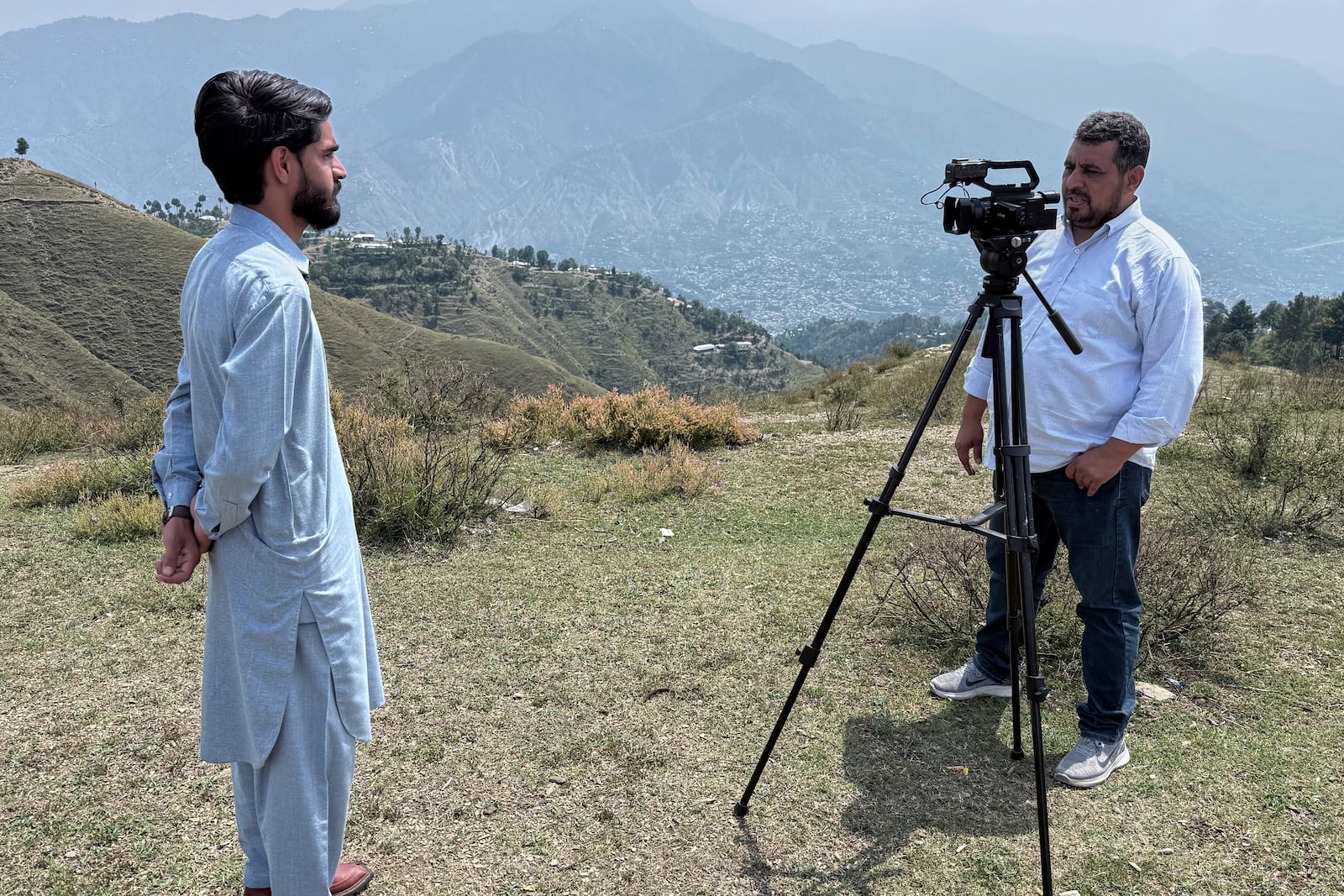 A cameraman records an interview with a villager during a government's organized trip for media to Bella Noor Shah, a mountainous village near Muzaffarabad, the capital of Pakistan administered Kashmir, Monday, May 5, 2025. (AP Photo/Muhammad Yousuf, Pool)