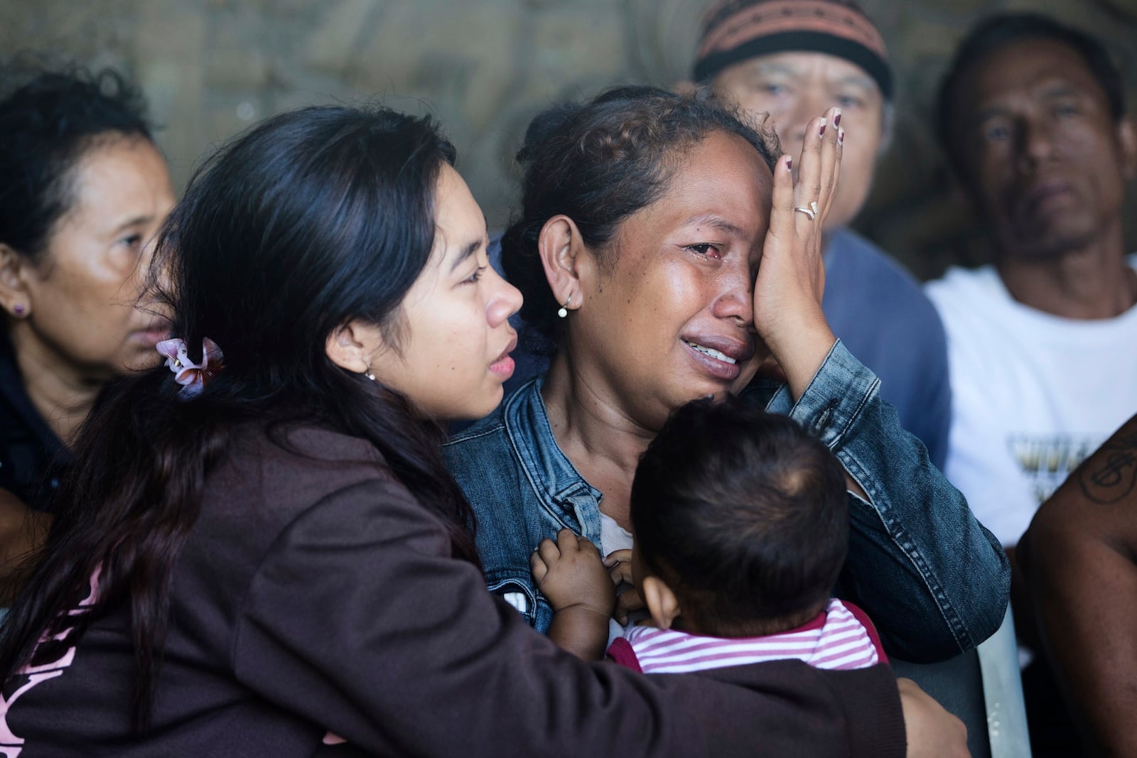 A relative of a passenger weeps after a ferry sank while en route to the resort island of Bali, in the waters off Banyuwangi, East Java, in Gilimanuk, Bali island, Indonesia, Thursday, July 3, 2025. (AP Photo/Firdia Lisnawati)