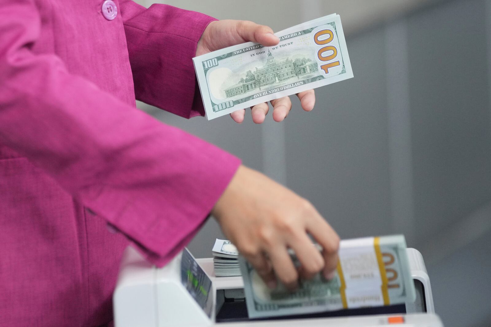 An employee counts U.S dollar banknotes using a machine at a money changer in Jakarta, Indonesia, Tuesday, April 8, 2025. (AP Photo/Tatan Syuflana)