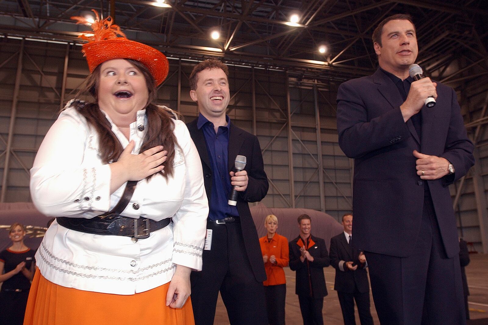 Australian actor Magda Szubanski, left, mocks her desire for American movie star John Travolta, right, during the unveiling of airline Jet Star's first plane in Sydney, May 10, 2004. (AP Photo/Rick Rycroft, File)