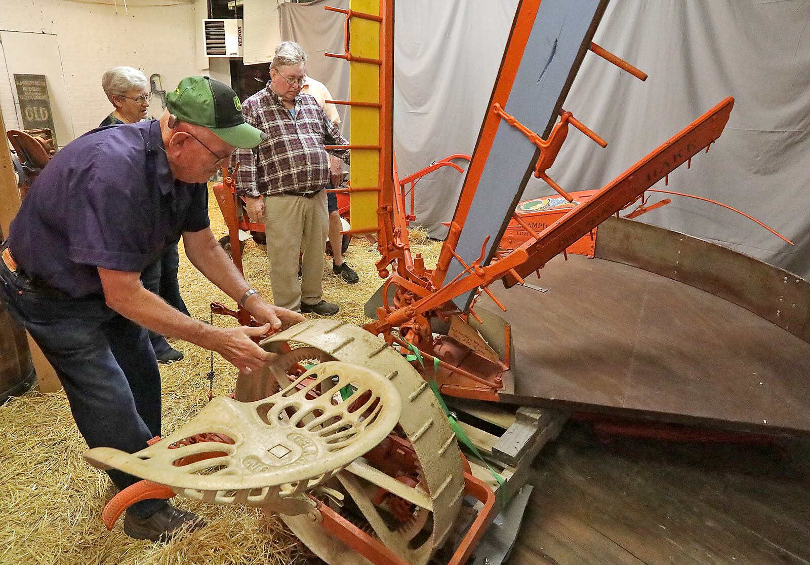Bob Wood turns the wheel and operates the Champion Reaper he and his wife, Sharon, had just delivered to Dan Hearlihy at his museum Tuesday. BILL LACKEY/STAFF