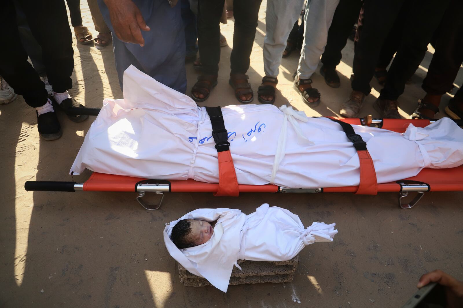 Mourners pray over the body of Soad Qeshtah, who died just hours after being delivered by emergency caesarean section. Her mother, seven-months pregnant Soad al-Shaer, was killed in an overnight Israeli airstrike on Khan Younis in the Gaza Strip, Monday, July 28, 2025. (AP Photo/Mariam Dagga)
