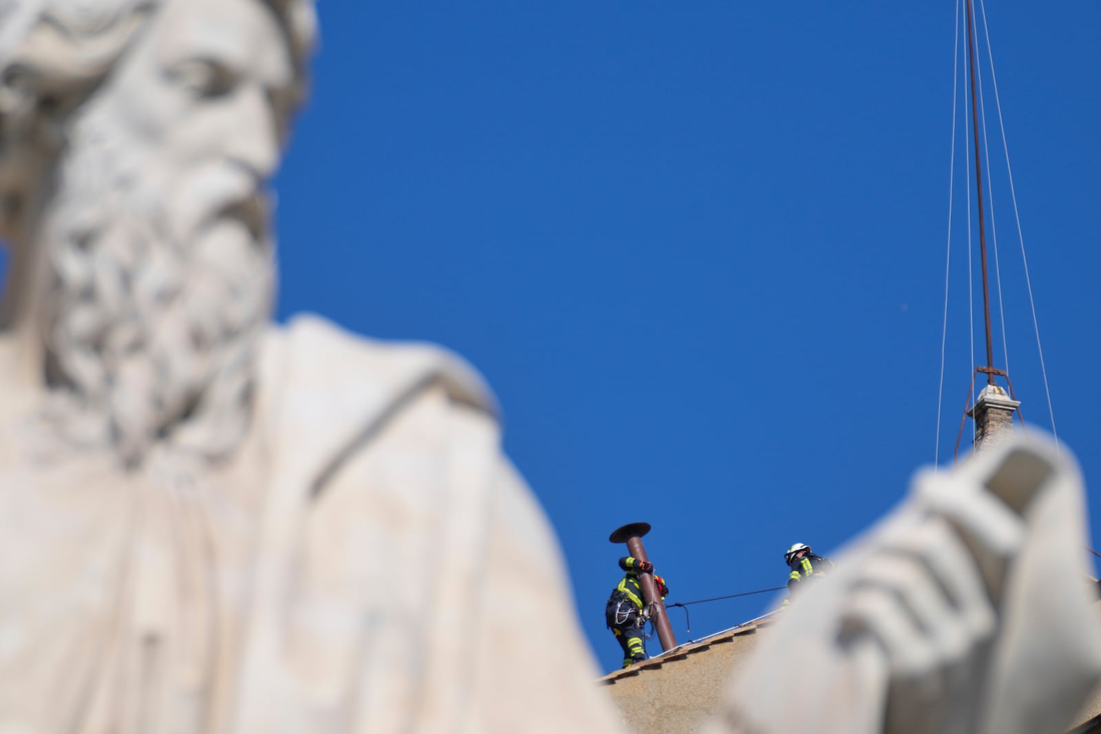 Firefighters place the chimney on the roof of the Sistine Chapel, where cardinals will gather to elect the new pope, at the Vatican, Friday, May 2, 2025. (AP Photo/Gregorio Borgia)