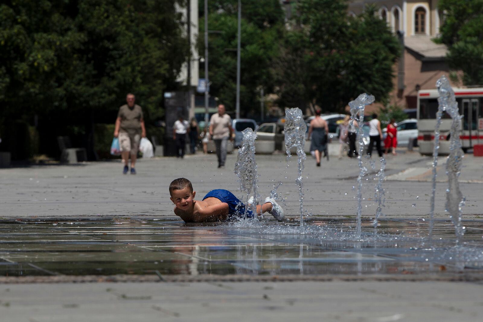 A boy plays in a fountain during hot weather in Kosovo's capital Pristina on Thursday, July 3, 2025. (AP Photo/Visar Kryeziu)
