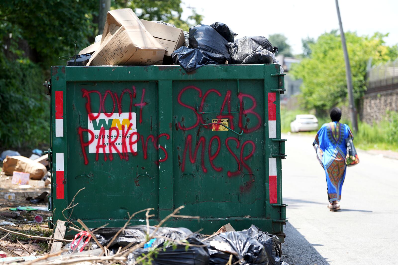 A woman walks past a garbage collection site, Wednesday, July 9, 2025, in Philadelphia. (AP Photo/Matt Slocum)