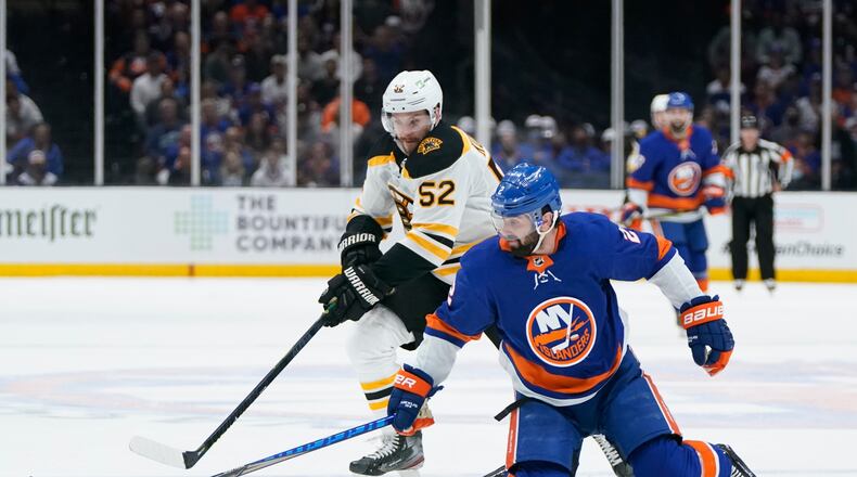 Boston Bruins' Sean Kuraly (52) and New York Islanders' Nick Leddy (2) reach for the puck during the third period of Game 3 during an NHL hockey second-round playoff series Thursday, June 3, 2021, in Uniondale, N.Y. (AP Photo/Frank Franklin II)