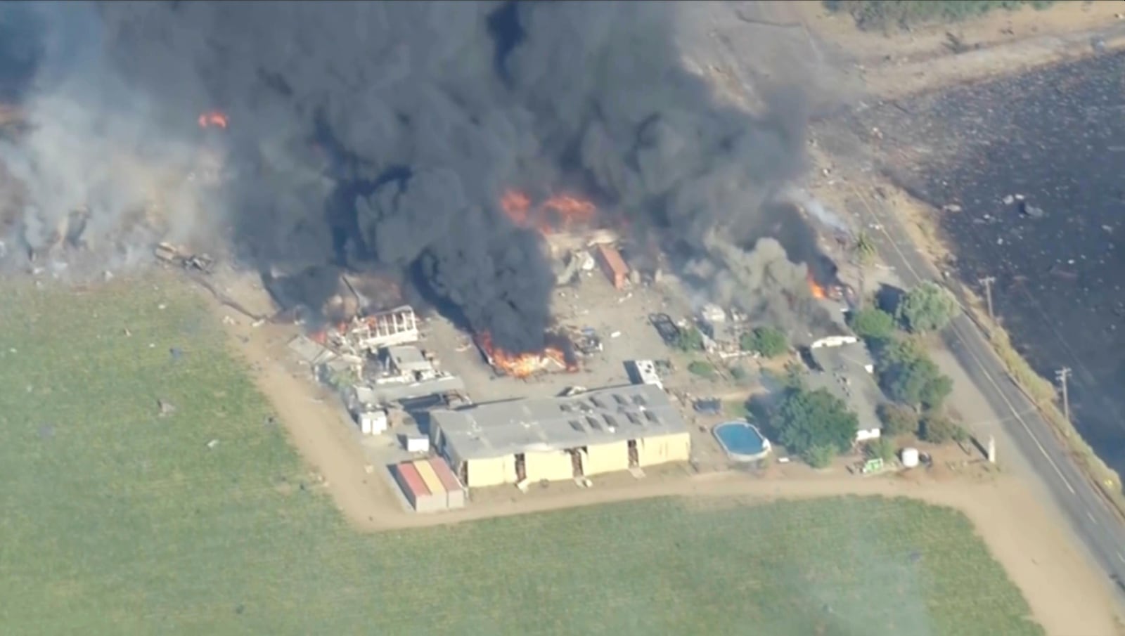 In this aerial image taken from video, smoke and flames rise from a fireworks warehouse explosion, July 1, 2025. (KGO via AP)