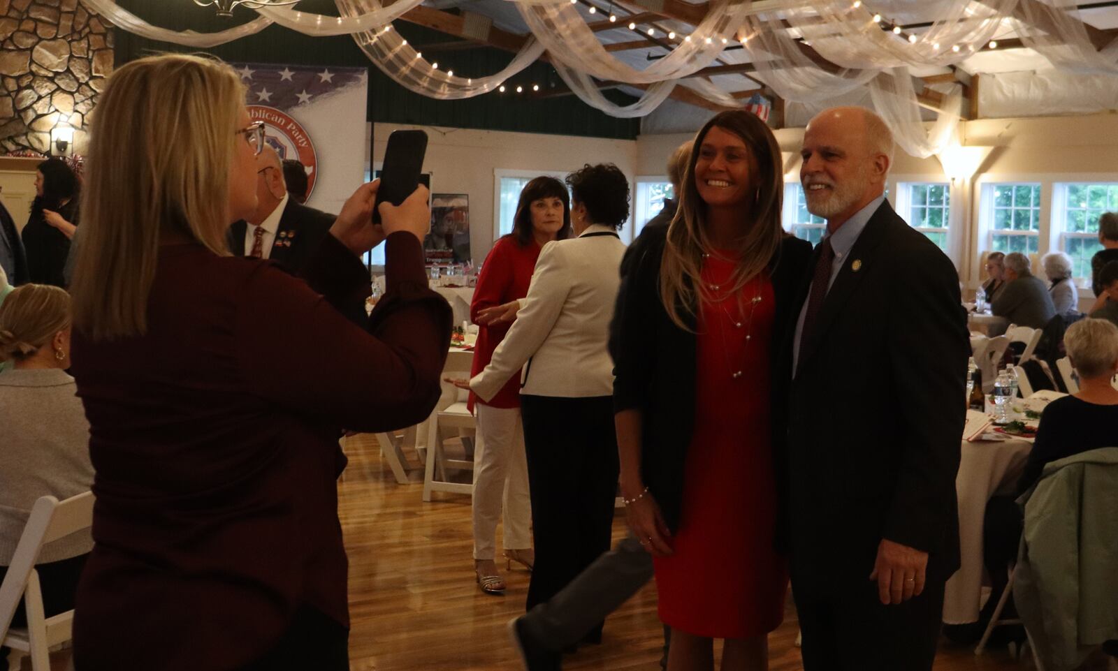 Clark County Auditor Hillary Hamilton snaps a photo of Ohio Sen. Kyle Koehler and Cassie Brake, of Express Employment, during the county's Reagan-Trump dinner Thursday, May 22, 2025. JESSICA OROZCO/STAFF