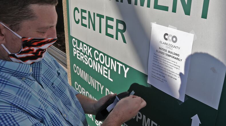 Mike Cooper, Clark County public information officer,  puts up signs announcing the temporary closing of the Clark County government offices at Springview Government Center Wednesday. BILL LACKEY/STAFF