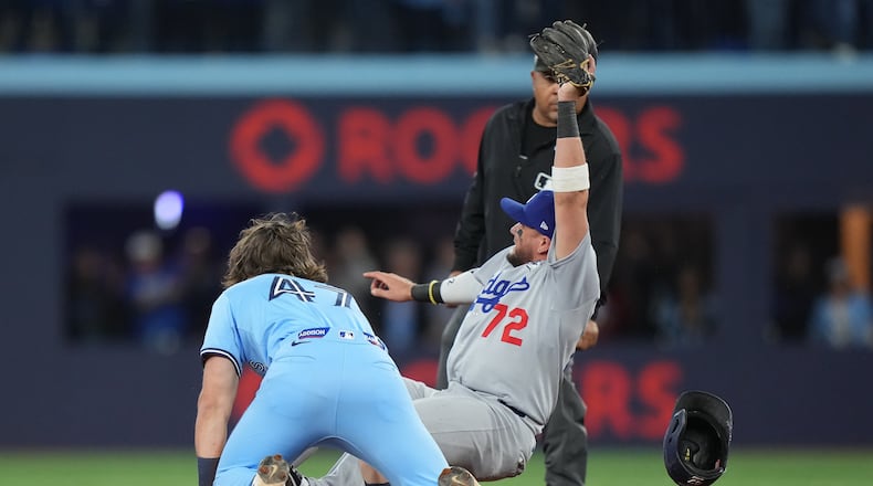 Los Angeles Dodgers second baseman Miguel Rojas (72) shows the ball to the umpire after forcing out Toronto Blue Jays' Addison Barger (47) at second to turn a double play to end the game during ninth inning Game 6 World Series playoff MLB baseball action in Toronto on Friday, Oct. 31, 2025. (Nathan Denette/The Canadian Press via AP)