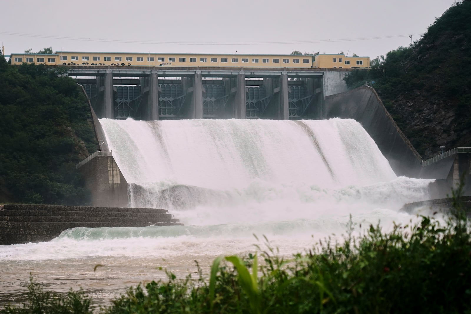 In this photo released by Xinhua News Agency, Water is discharged from Miyun reservoir after continuous rain fall triggers alerts, in Miyun District in north of Beijing on July 27, 2025. (Zhang Chenlin/Xinhua via AP)