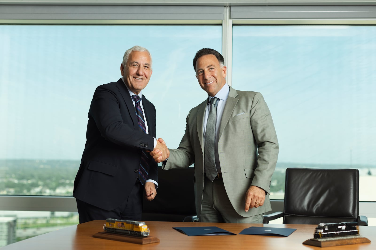 In this photo provided by Union Pacific shows from left, Union Pacific CEO Jim Vena shakes hands with Norfolk Southern CEO Mark George at the meeting where both men signed the agreement to merge the two railroads they lead to create the first transcontinental railroad in the United States on Monday, July 28, 2025 in Omaha, Neb. (Bill Sitzmann/Union Pacific via AP)