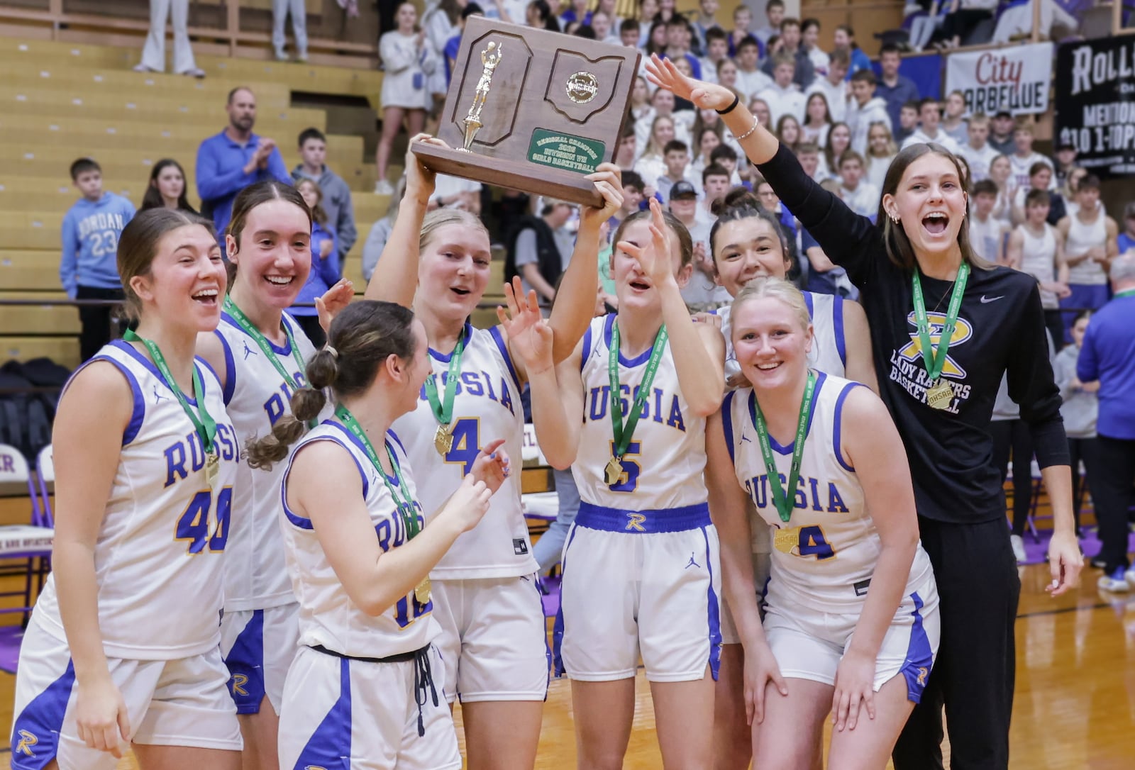 Russia players celebrate shortly after being presented with a Division VII regional championship trophy following a 40-32 win over Cedarville on Saturday, March 7 at Vandalia-Butler's Student Activity Center. The Raiders captured the program's first regional title. BRYANT BILLING / STAFF