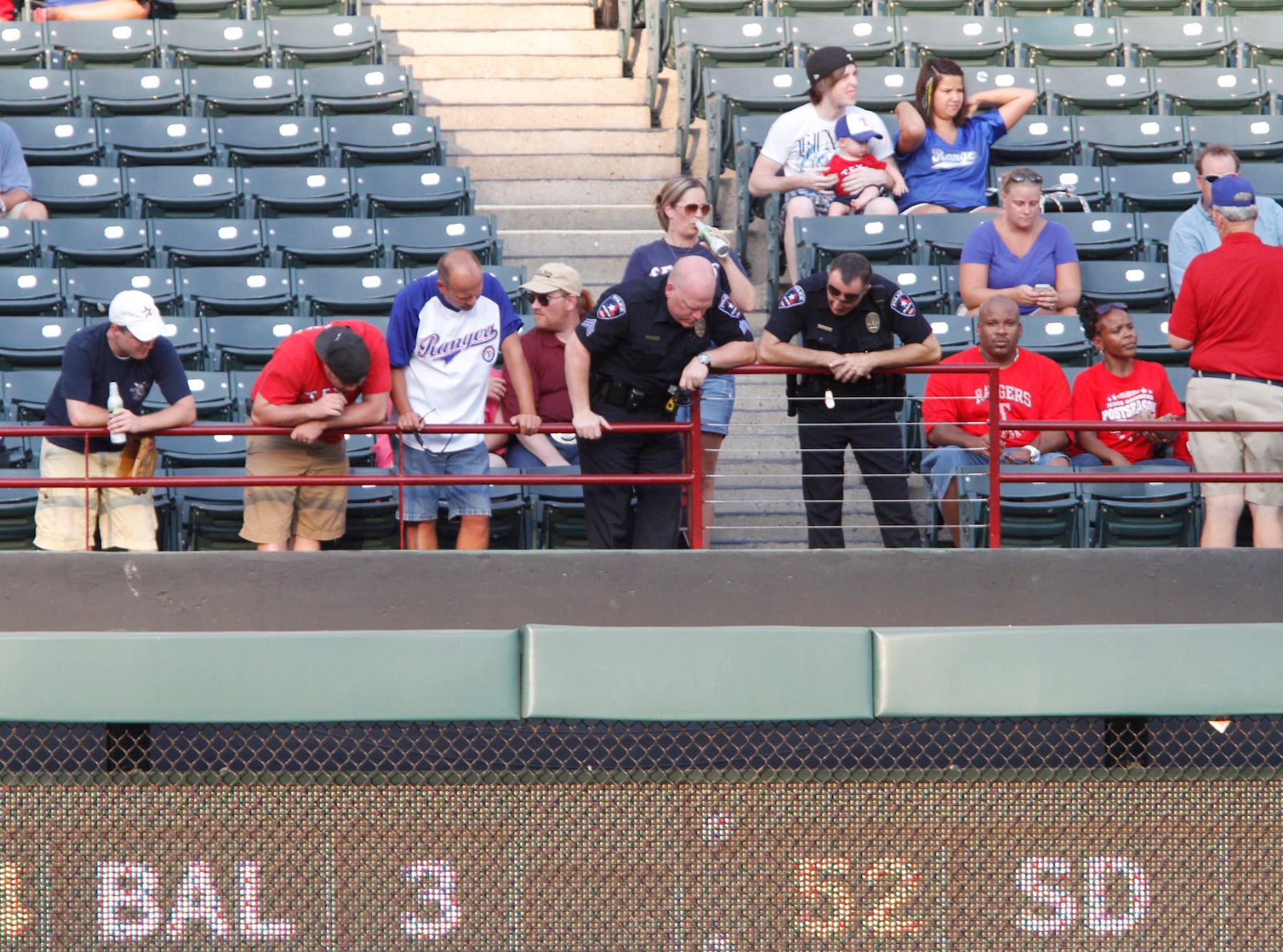 FILE - Police and fans look over the railing where a fan fell from the stands during the second inning of a baseball game between the Texas Rangers and the Oakland Athletics, Thursday, July 7, 2011, in Arlington, Texas. (AP Photo/Jeffery Washington, File)