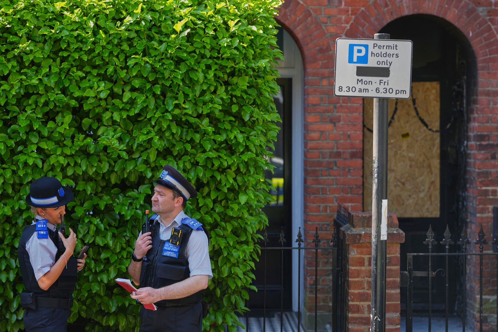 Police Community Support Officers stand near the fire damaged doorway of a house belonging to British Prime Minister Keir Starmer in Kentish Town in London, Tuesday, May 13, 2025. (AP Photo/Kirsty Wigglesworth)