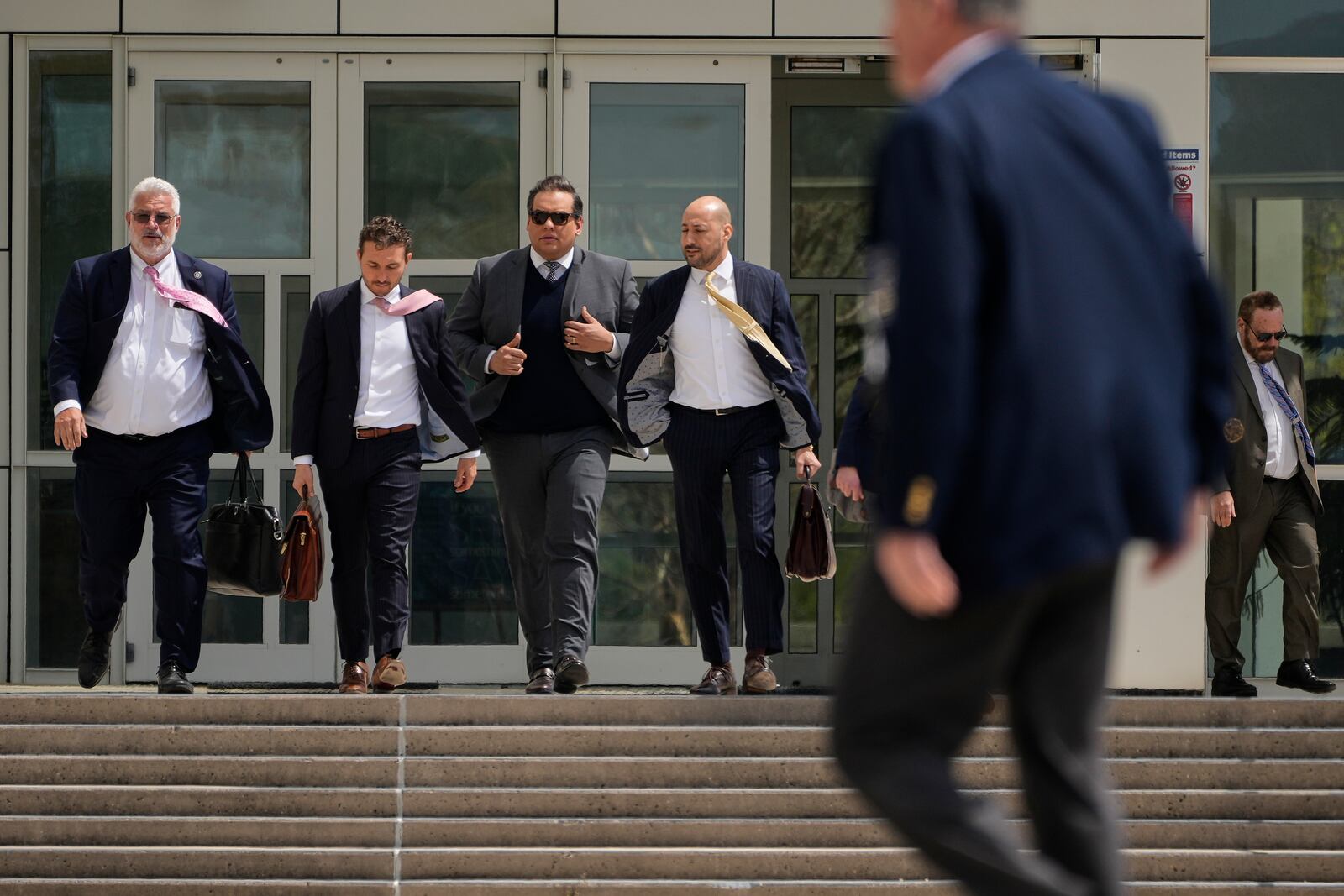 Former U.S. Rep. George Santos, center, leaves federal court after being sentenced to more than seven years in prison for fraud and identity theft, Friday, April 25, 2025, in Central Islip, N.Y. (AP Photo/Julia Demaree Nikhinson)