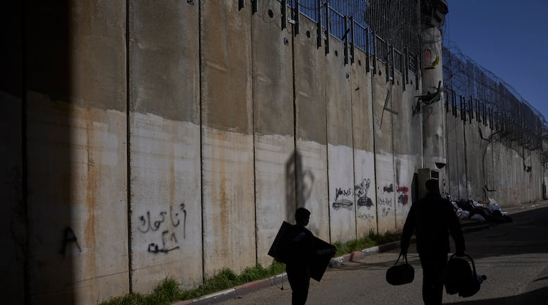 Palestinians walk along the separation barrier between the West Bank and east Jerusalem neighborhood of Beit Hanina, Sunday Feb. 15, 2026. (AP Photo/Ohad Zwigenberg)