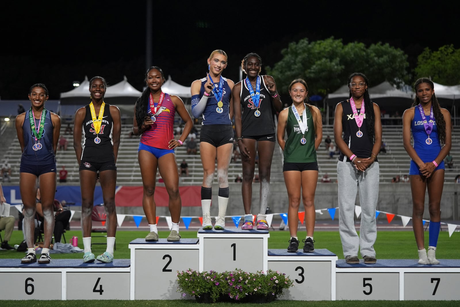 AB Hernandez, center left, shares the first-place spot on the podium with Kira Gant Hatcher during a medal ceremony for the triple jump at the California high school track-and-field championships in Clovis, Calif., Saturday, May 31, 2025. (AP Photo/Jae C. Hong)