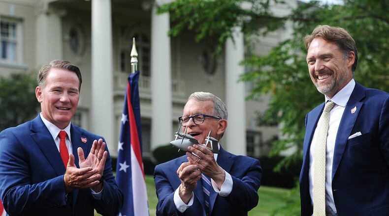 Lt. Gov. Jon Husted, left, and Ohio Gov. Mike DeWine applaud Joby Aviation Inc. founder JoeBen Bevirt, at far right, at Hawthorn Hill, the home of Orville Wright, in Oakwood after he announced Monday, Sept. 18, 2023, his company's pledge to bring thousands of jobs to the region at a facility near Dayton International Airport that specializes in the production of "flying cars." MARSHALL GORBY\STAFF