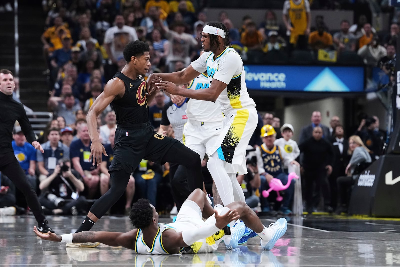 Indiana Pacers guard Bennedict Mathurin (00) falls to the court as center Myles Turner pushes Cleveland Cavaliers forward De'Andre Hunter (12) in the first half of Game 4 in the Eastern Conference semifinals of the NBA basketball playoffs in Indianapolis, Sunday, May 11, 2025. (AP Photo/Michael Conroy)